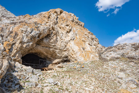 ancient cave, the entrance to which is closed by a metal gratingの写真素材