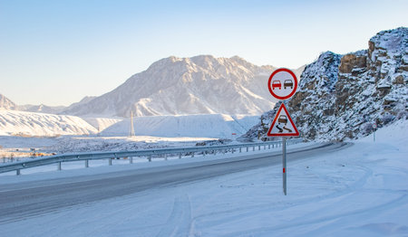 road sign on a slippery road against the background of a winter mountain landscape