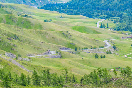 view from the top of the mountain, from the pass to the winding dangerous mountain road against the background of the valley landscapeの写真素材