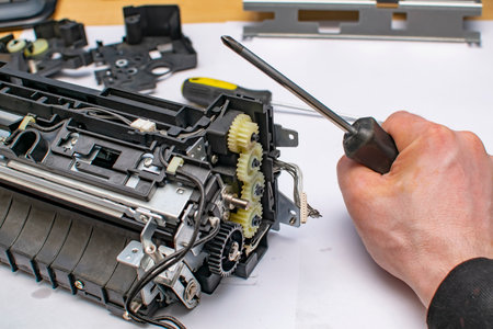 the hand of the service center master squeezes a screwdriver near the disassembled gearboxの写真素材