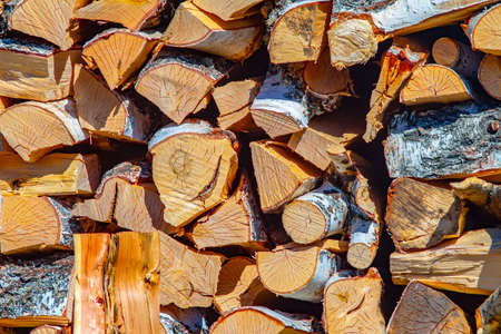 view of a woodpile of chopped firewood with birch bark, stacked in a stack in full screenの写真素材