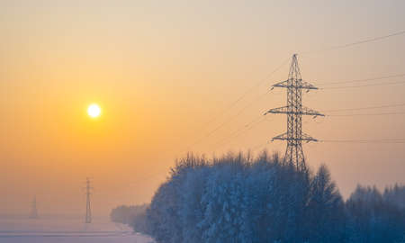 high voltage power transmission lines in a thick frosty foggy hazeの写真素材