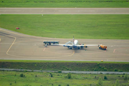 rear view of a passenger plane in the parking lot next to a fuel tanker and a bus with passengersの写真素材