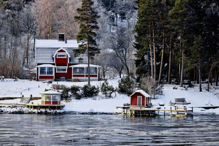 Sweden house in the wintertime. Nature on the shore of the fjord.の写真素材