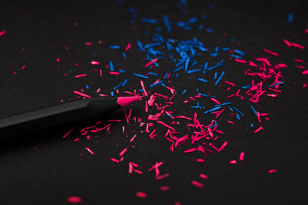 Black colored pencil, on black background, and shavings from the pencils.