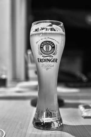 Dusseldorf, Germany 06,06,2016 : Glowing weiss glass of light Erdinger Beer on a pub. bokeh background.のeditorial素材