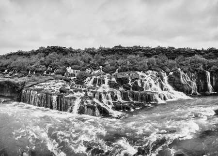 Incredibly beautiful Hraunfossar Waterfall. Lava waterfalls. waterfall flowing down from the lava fields on the canyon of the hvita river, Popular tourist attraction in Iceland. Iceland's clean water.の写真素材