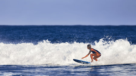 Beautiful young woman learns to stand on a surfboard. Surfer school. Woman in swimsuit in hot summer...