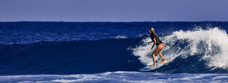 Beautiful young woman is learning to stand on a surfboard. Surf school. Water sports, Atlantic ocean...