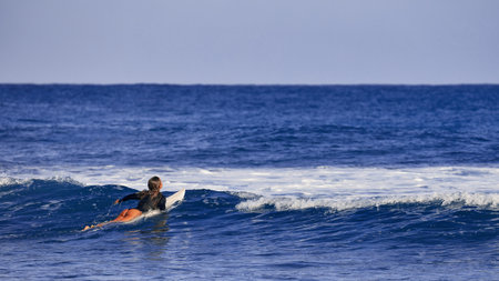 Surfer girl waiting for a wave. Surfer school. Beautiful young woman in swimsuit goes into ocean in hot summer day. Surfer on the wave. beautiful ocean wave. Water sport activity.の写真素材