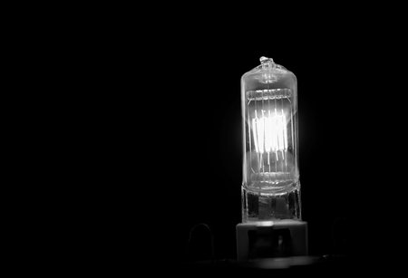 Burning lightbulb filament. Electric tungsten light bulb on a black background