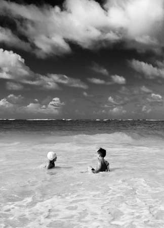 Small children on the sandy beach. Little boy and a little girl playing in the water on a clean beach. Paradise beach and the kids.の写真素材