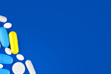 Assorted pharmaceutical medicine pills, tablets and capsules on blue background.の写真素材