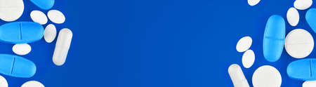 Assorted pharmaceutical medicine pills, tablets and capsules on blue background.の写真素材
