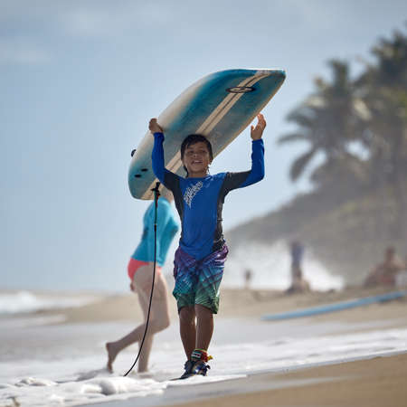 Boy with Board on the beach. young surfer. Surfer school. Water sport activity. Atlantic Ocean, Dominican Republic. 29 12 2016のeditorial素材