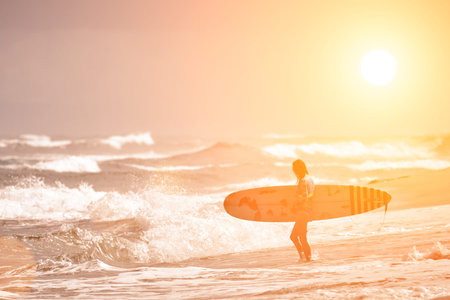 Surfers beach. Beautiful surfer girl on the beach. Water sport activity.