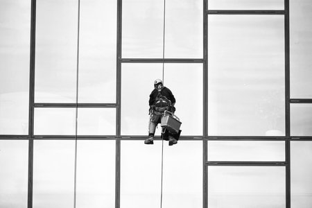Window cleaners at work. Window cleaner, in the suspension system. Industrial mountaineering.の写真素材