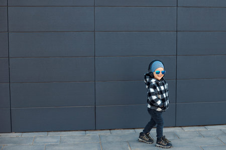 Cool and fun child listen to music playing, walking in earphones on dark blue wall background....