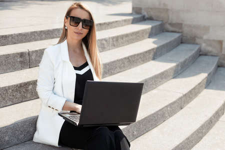 Street style portrait of serious business woman with laptopの写真素材