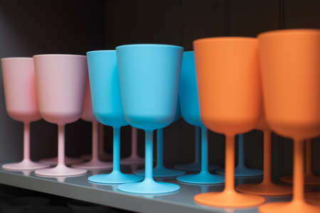 Colorful wine glasses in pink, blue and orange colors. Multicolored dishes in the kitchen barの写真素材