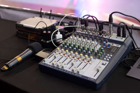 Workplace with audio mixing console and microphone of sound engineer control music and light in concert near the stage.の素材 [FY310169769804]