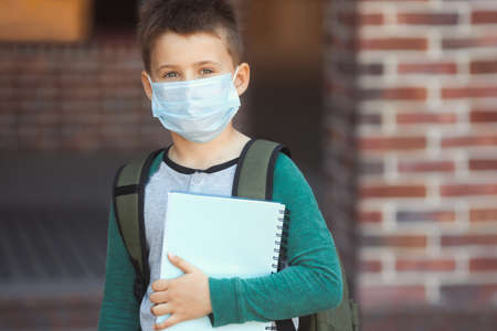 Little boy in protective mask and backpack on face goes to school. New normal.の写真素材