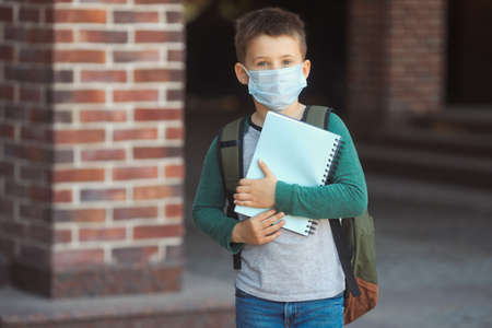 Little boy in protective mask and backpack on face goes to school. New normal.の写真素材