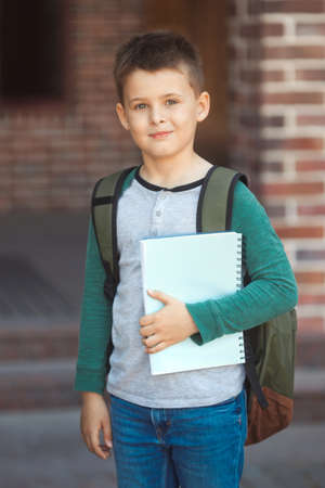 Smiling little boy 6-7 years old goes to school in casual clothes and backpackの写真素材
