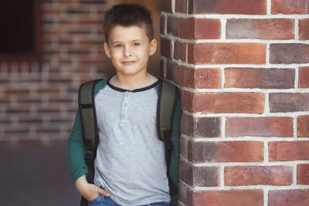 Smiling little boy 6-7 years old goes to school in casual clothes and backpackの写真素材