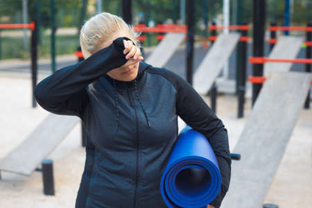 Young overweight woman on the street workout place after sports. Tired plus-size girl in sportswear training outdoorの写真素材