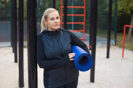 Young overweight woman on the street workout place after sports. Tired plus-size girl in sportswear training outdoorの写真素材