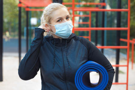 Tired blonde plus-size girl in sportswear maintains social distance,tries to lose weight with training outdoor.の写真素材