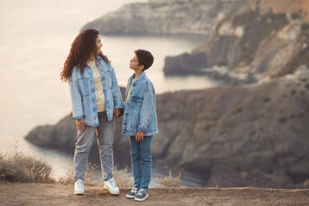 Lifestyle photo of happy mom and teen boy hold the handle together on the top of hill. Spanish tourists woman and child at vacation.の写真素材