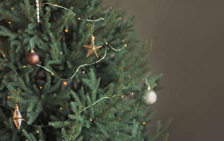 Trendy minimalistic green Christmas tree decorated with toys and lights on a gray background. Copy space.の写真素材