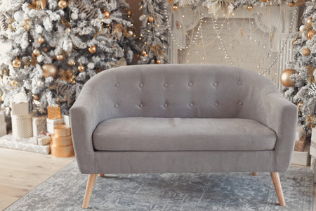 Hall room interior with a couch, fireplace with candles and decorated Christmas tree with gifts....