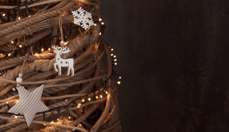 Close up night photo of decorated creative eco-friendly homemade wooden Christmas tree with warm lights and ecological toys from natural materials. Copy space.の写真素材