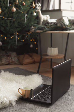 Vertical pfoto of freelance workiplace during the Christmas lockdown. A laptop and a cup of coffee...