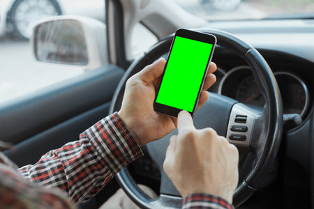 Close up man driver hands holding smartphone and using app on with chroma key in carの写真素材
