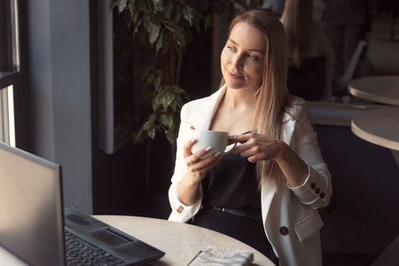 Business woman working with laptop in cafe with dark black interiorの写真素材
