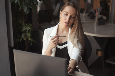 Business woman working with laptop in cafe with dark black interiorの写真素材