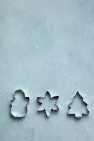 The concept of the New year and Christmas 2019. Cookie cutters in the form of snowflakes, Christmas trees, snowman lie on a blue background. Decor. Postcardの写真素材