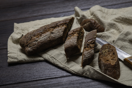 Freshly baked homemade rye bread with herbs and garlic butter.  On a dark brown wooden background. Rustic style. Place for text. Top viewの写真素材