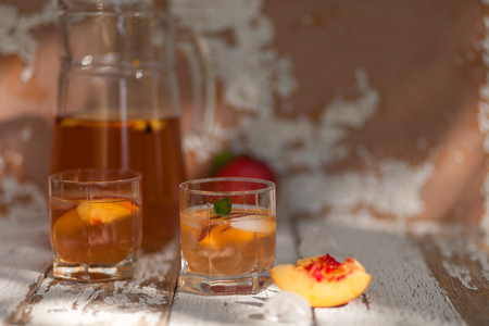 Ice tea and nectarine. Jag, two glasses.  A refreshing summer drink. The concept of summer. On a white wooden  background. Side viewの写真素材