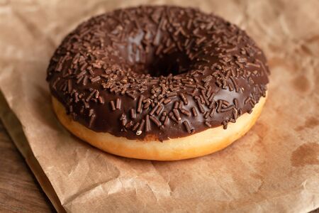 Chocolate-coated doughnut and chocolate sprinkles close-up. On parchmentの写真素材