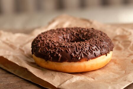 Chocolate-coated doughnut and chocolate sprinkles close-up. On parchmentの写真素材