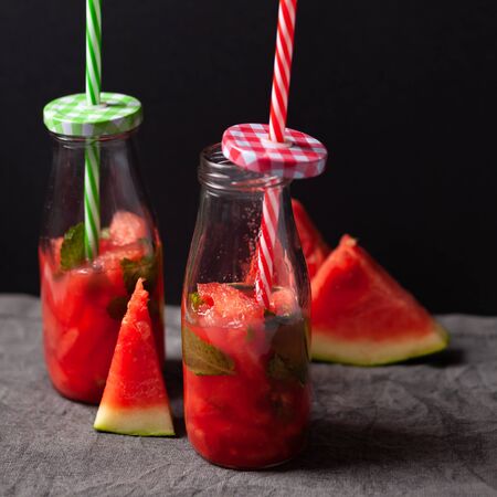 Homemade refreshing drink or lemonade made from watermelon and mint in small bottles. On a dark backgroundの写真素材