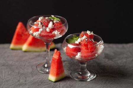 A delicious dessert of watermelon and cream cheese, decorated with a leaf of mint and chia seeds. In a glass dishの写真素材