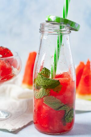 Homemade refreshing drink or lemonade made from watermelon and mint in small bottles. On a blue backgroundの写真素材