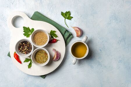 Set of fragrant spices on a wooden white Board. Pepper, mustard seeds, herbs on a concrete blue background. Food concept. Space for text, no peopleの写真素材
