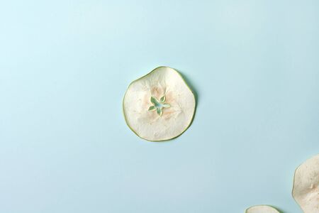 Dried pieces of Apple chips on a blue isolated background. Homemade harvesting, healthy and organic food, autumn harvest, vegetarian food. Space for textの写真素材